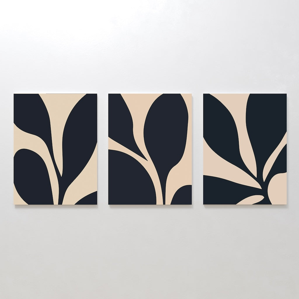 The Noir Blossom Set of 3 features minimalist canvases with abstract navy and beige leaf-like shapes, arranged side by side to create a cohesive modern wall art triptych on any white wall.