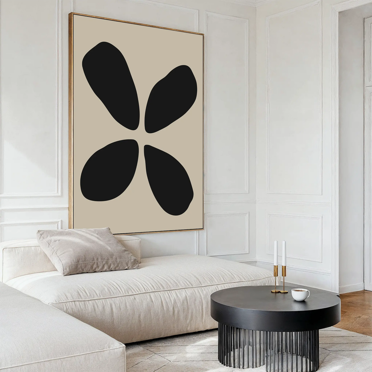 A modern living room with a white sectional sofa, a round black coffee table, and minimalist wall art—Noir Botanica Canvas Art featuring four black shapes on a beige background—hanging on the wall.