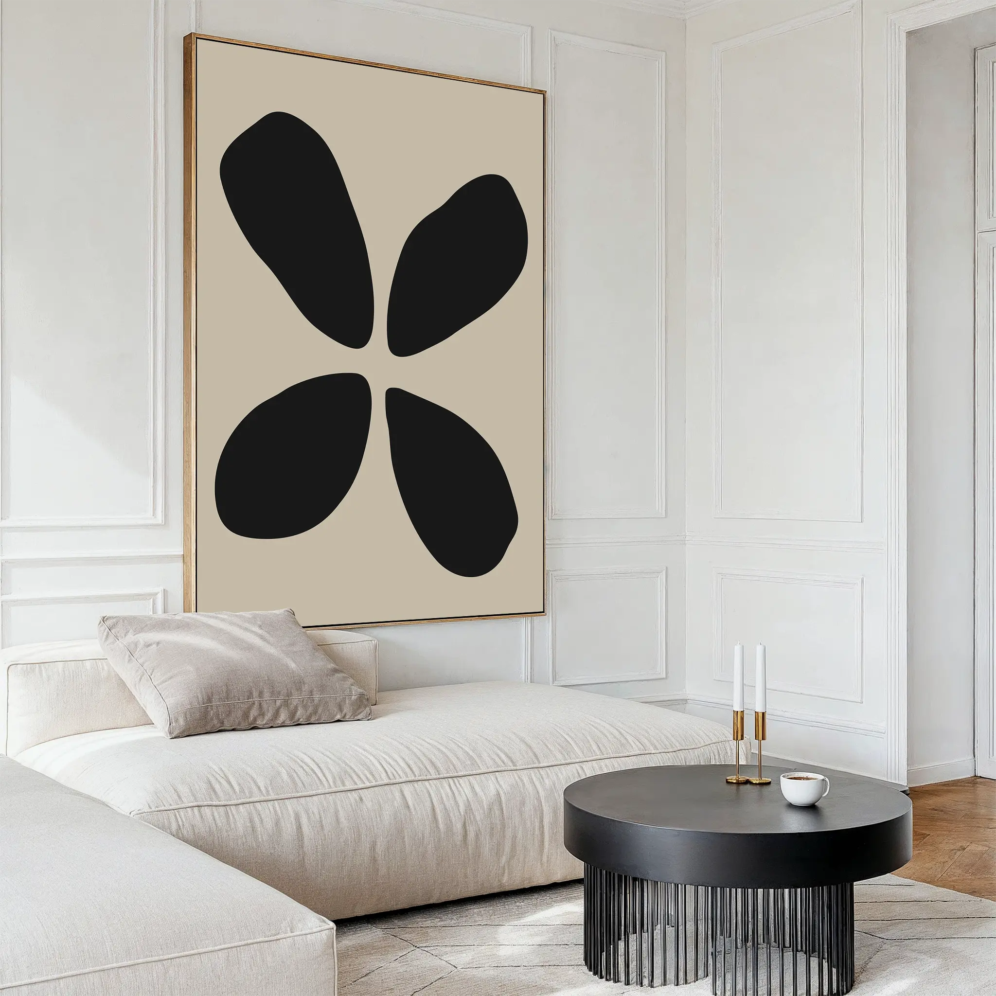 A modern living room with a white sectional sofa, a round black coffee table, and minimalist wall art—Noir Botanica Canvas Art featuring four black shapes on a beige background—hanging on the wall.