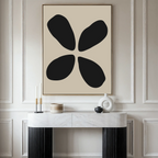 A modern living space featuring the Noir Botanica Canvas Art—a large abstract piece with four black shapes on a beige background—hung above a white console table decorated with candles, a vase, and modern decor.