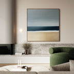 A modern living room with a green armchair, marble surfaces, a minimalist wall light, a vase of dried branches, and Ocean Edge Canvas Art—a striking large abstract beach scene—displayed on the wall.