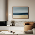 A modern living room with a beige armchair, a marble shelf adorned with dried flowers, and Ocean Edge Canvas Art – Horizontal above. Soft lighting highlights the calm, minimalist vibe.