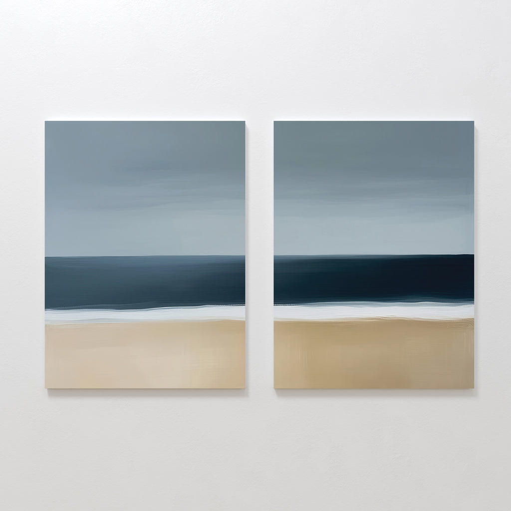 The Ocean Edge Set of 2 features square paintings with a minimalistic seascape—sandy beach, deep blue ocean, and cloudy sky in soft brushstrokes—perfect for serene coastal decor in your living room.