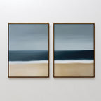 The Ocean Edge Set of 2 features framed abstract paintings in soft blue, gray, and beige, capturing the sky, sea, and beach for calming coastal wall art—ideal for serene living room decor.