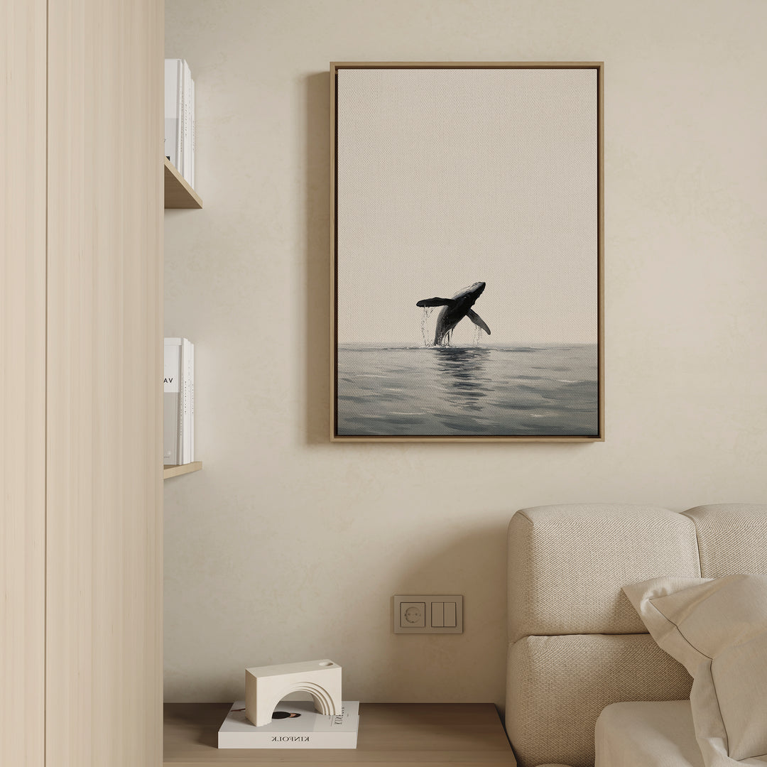 The Ocean Leap Canvas Art features a breaching whale above the ocean, displayed on a beige wall over a light sofa, with a bookshelf and decorative object nearby.