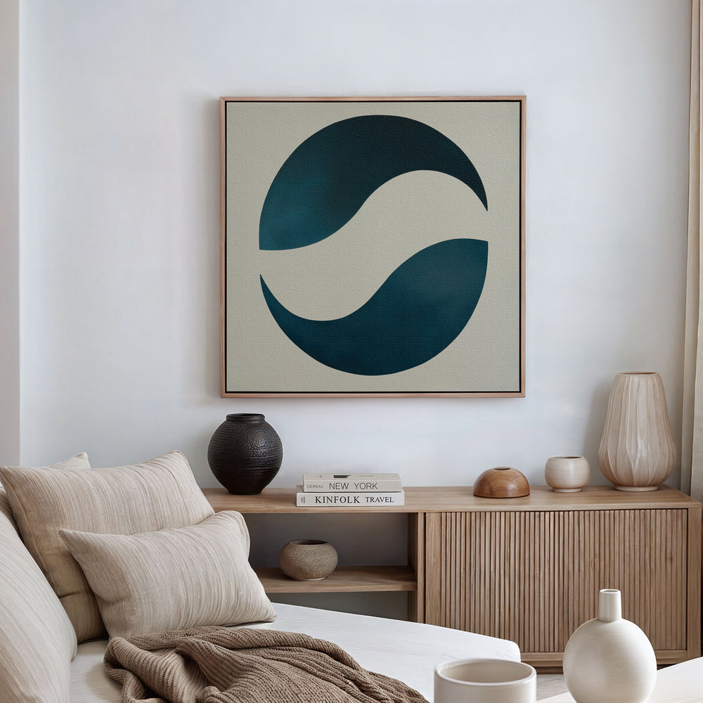 A modern living room with a light sofa, beige cushions, wooden sideboard, decorative ceramics, and the Ocean Orbit Canvas Art—an abstract piece with dark blue curves on a cream background—hanging above.