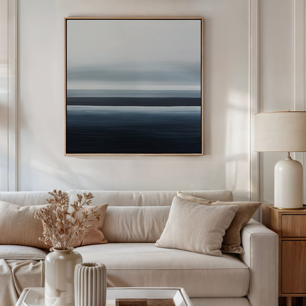 A modern living room featuring a beige sofa, neutral throw pillows, coastal vases with dried flowers, and the Oceanic Blur Abstract Canvas Art in blue and gray tones creates elegant decor.
