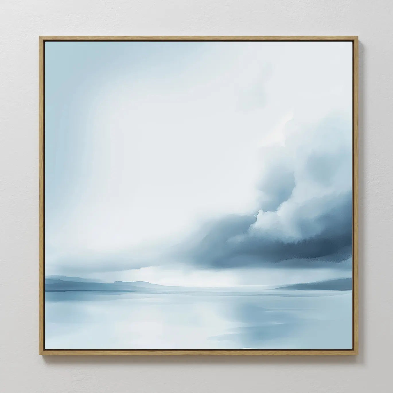 The Oceanic Overcast Canvas Art features a framed abstract seascape in soft blue and white tones, portraying a tranquil ocean, distant land, and a dramatic cloudy sky for a serene atmosphere.