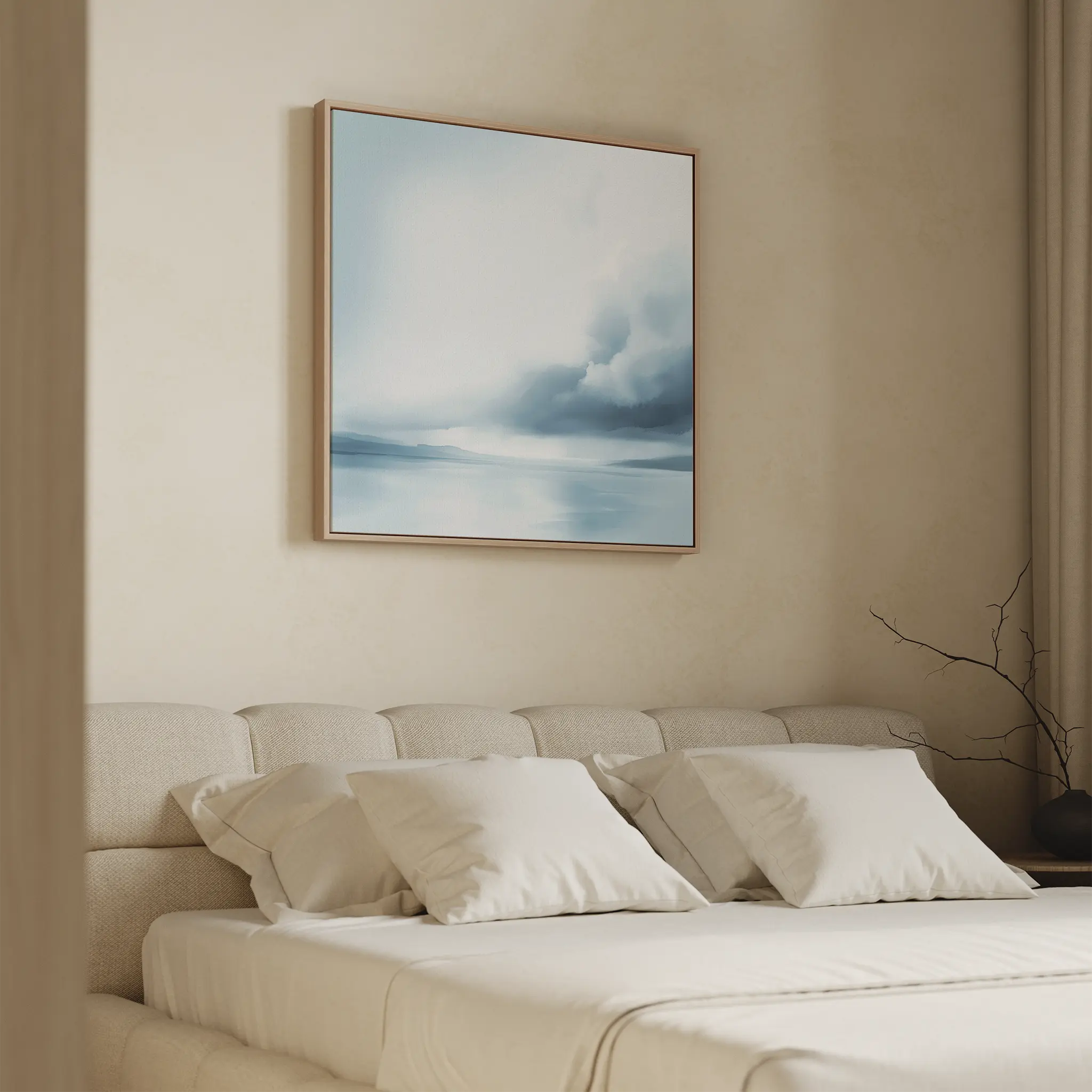 A beige, modern bedroom features a neatly made bed with four white pillows and minimal decor. Above the bed hangs the Oceanic Overcast Canvas Art in blue and white, adding a calming touch beside a bare branch in a vase on the nightstand.