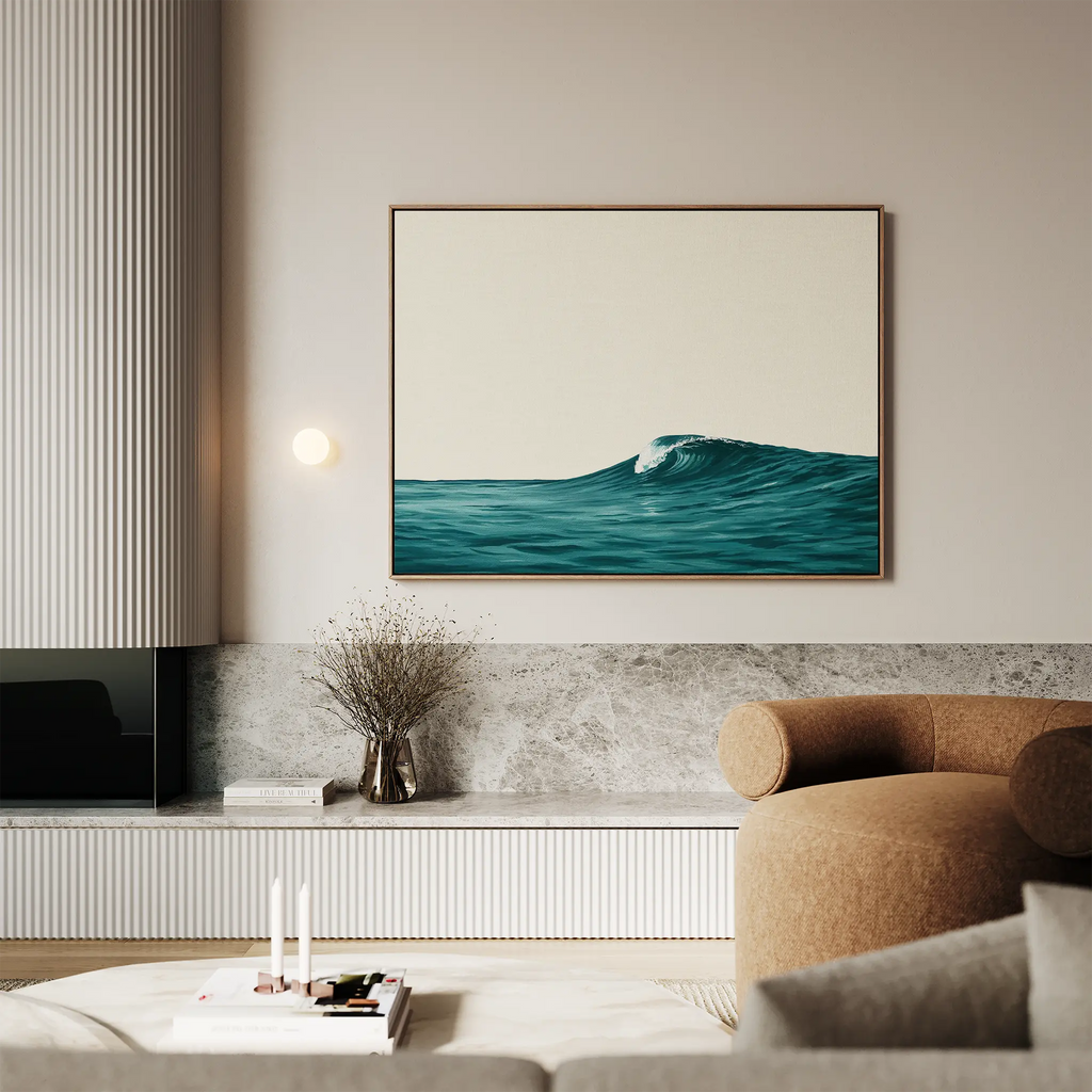 A modern living room features a beige sofa, marble accents, and minimalist decor; the Oceanside Crest Canvas Art hangs above a sideboard with a vase of dried branches, completing the chic coastal style.