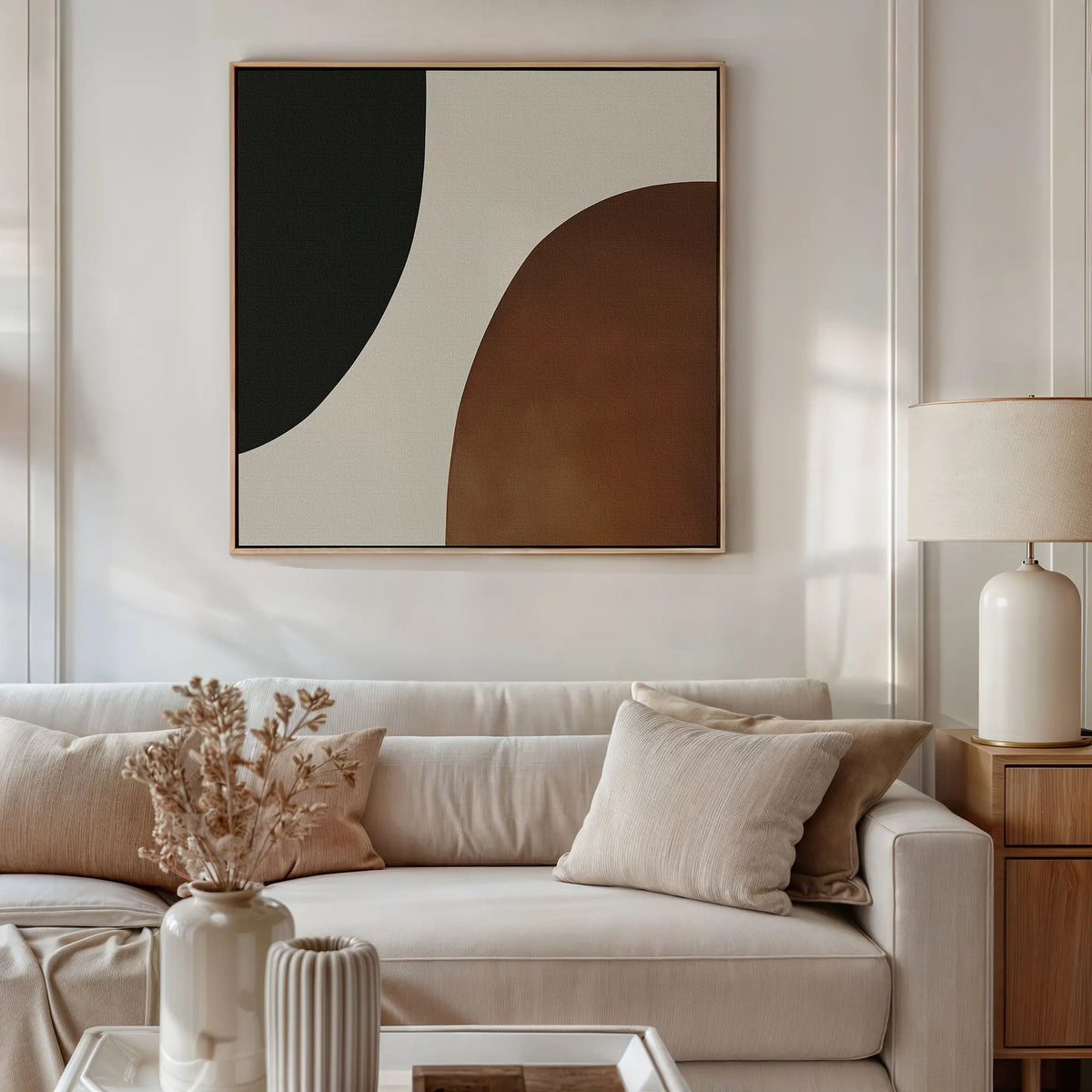 A modern living room with a beige sofa, neutral cushions, a wooden side table with a ceramic lamp, dried flowers in a vase, and Organic Balance Canvas Art—modern abstract wall decor for minimalist style.
