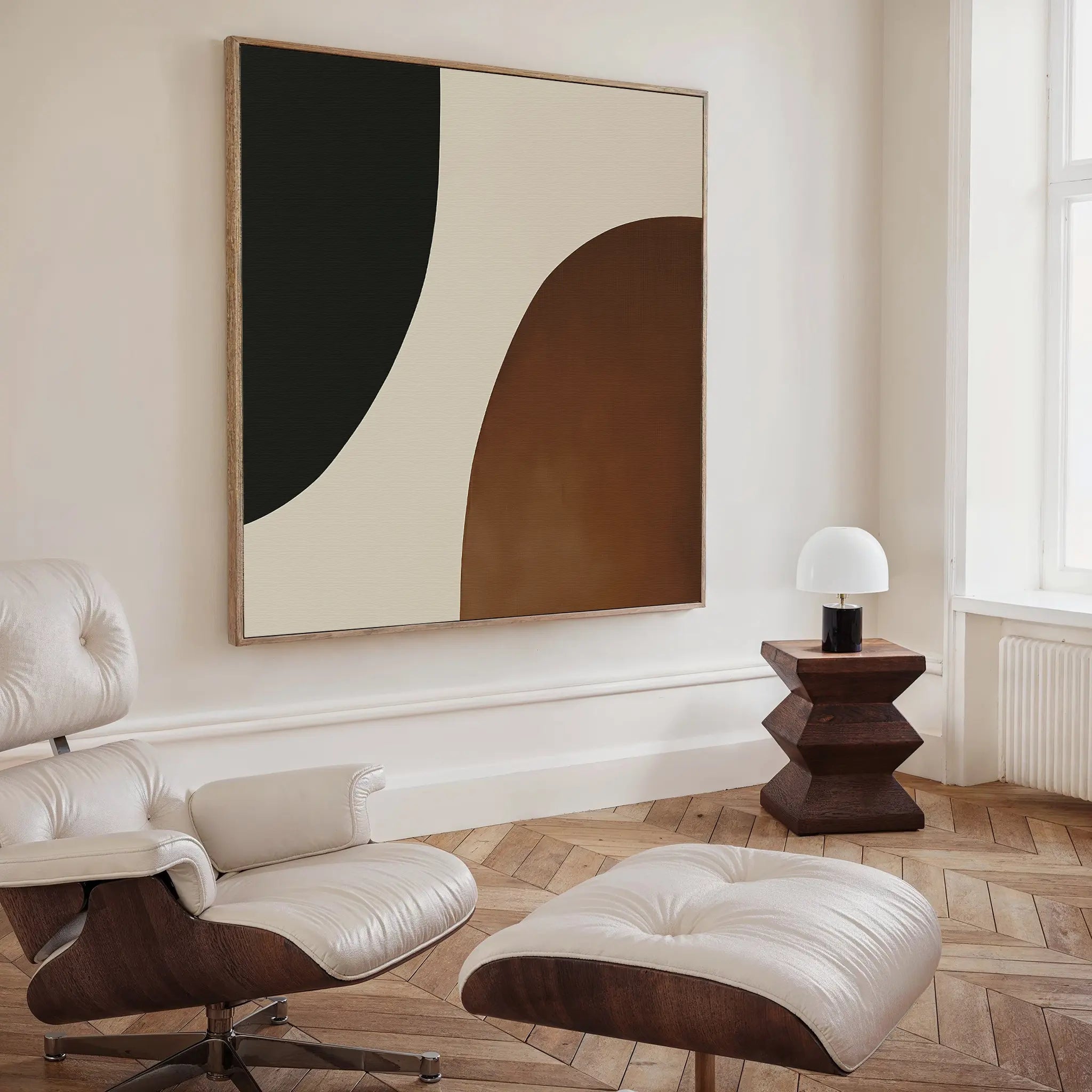 A modern living room features a white lounge chair and ottoman, dark wood side table with dome lamp, herringbone floors, and the Organic Balance Canvas Art in neutral tones for sophisticated minimalist decor.