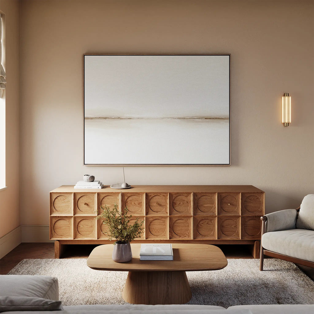 A minimalist living room featuring a wooden sideboard, the Pale Desert Canvas Art, coffee table with books, vase of flowers, light rug, neutral-toned sofa, and soft beige walls—perfect inspiration for chic decor.