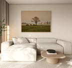 A modern living room with a light beige sectional, wooden coffee table, and countryside decor features the Pasture Morning Canvas Art, depicting horses grazing in a green field. Natural light enhances the tranquil rural charm of the space.