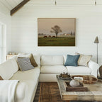 A cozy living room with a white sectional sofa, assorted throw pillows, a wooden coffee table with decor, and the Pasture Morning Canvas Art featuring horses in a field displayed above the seating area.