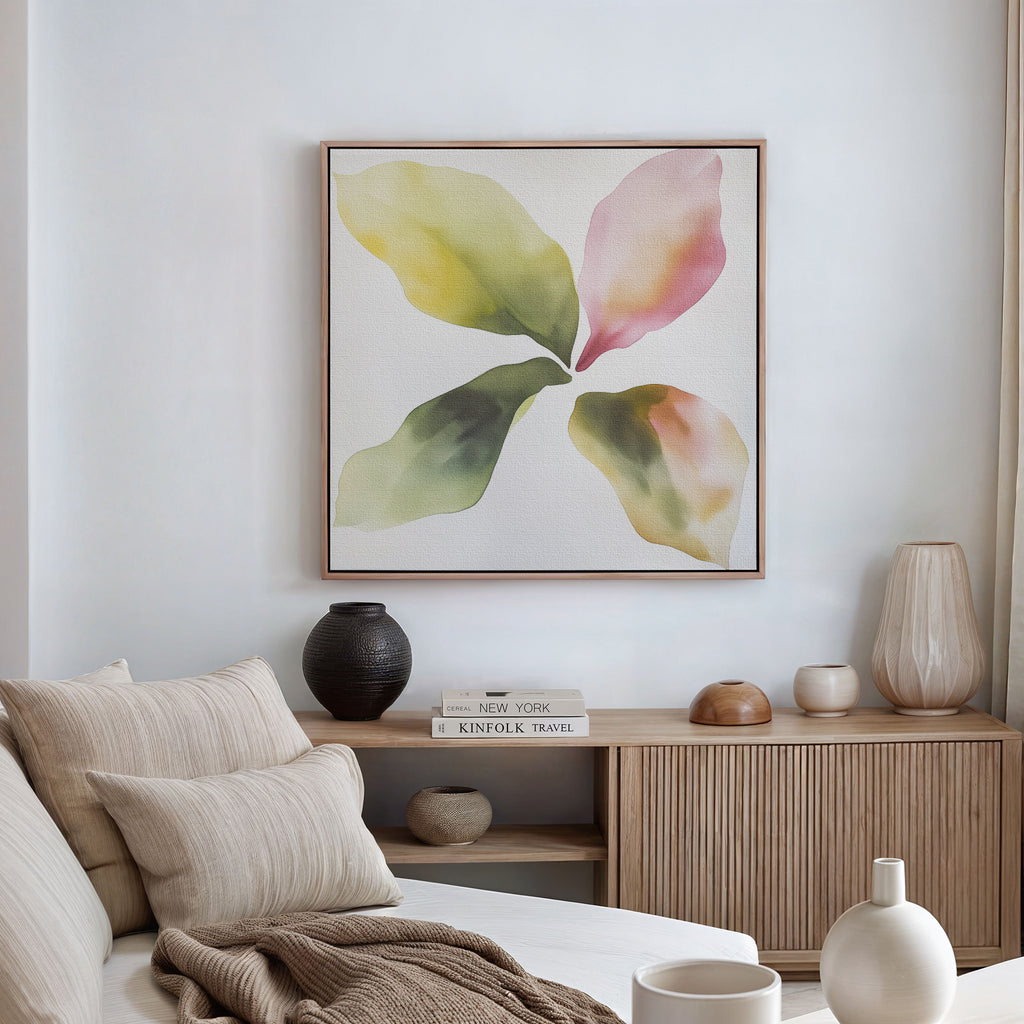 A modern living room featuring a neutral sofa, striped cushions, light wood cabinet, decorative accents, and the Petal Hues Canvas Art—a large abstract floral print in soft greens, yellows, and pinks—displayed on a white wall.