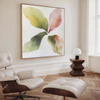 A modern living room with a white leather lounge chair and ottoman, a wooden side table with a white lamp, and the Petal Hues Canvas Art featuring large abstract floral designs in green, yellow, and pink tones on the wall.