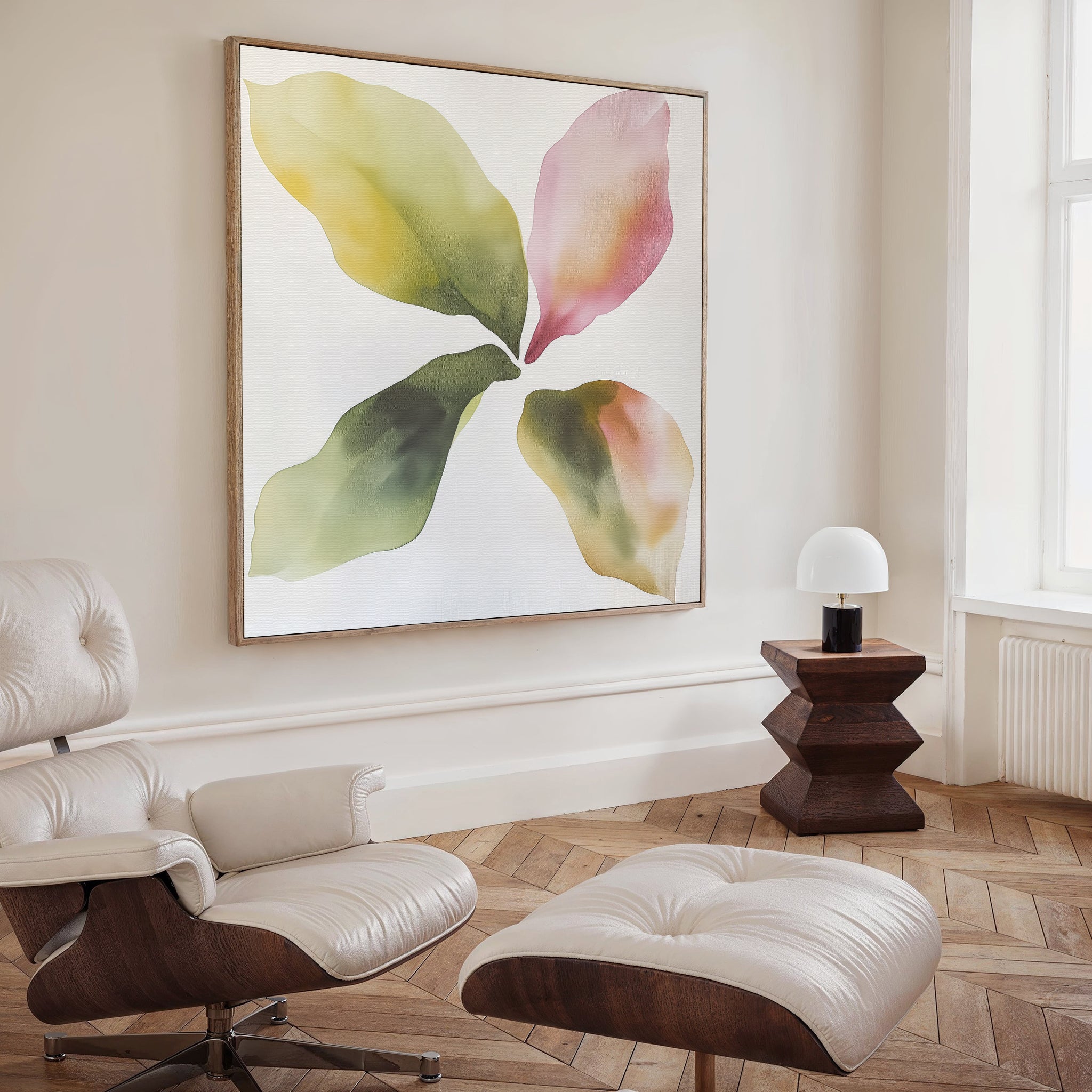 A modern living room with a white leather lounge chair and ottoman, a wooden side table with a white lamp, and the Petal Hues Canvas Art featuring large abstract floral designs in green, yellow, and pink tones on the wall.