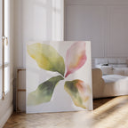 The Petal Hues Canvas Art, featuring an abstract floral design with four colorful leaf-like shapes in green, yellow, and pink, adds a vibrant touch to a bright, modern living room with wood flooring and neutral furniture.