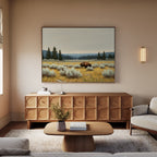 A cozy living room with a wooden sideboard, coffee table, beige sofa, and the Prairie Silence Canvas Art featuring a bison in a grassy field above the sideboard. A vase with flowers on the table completes the nature-inspired decor.