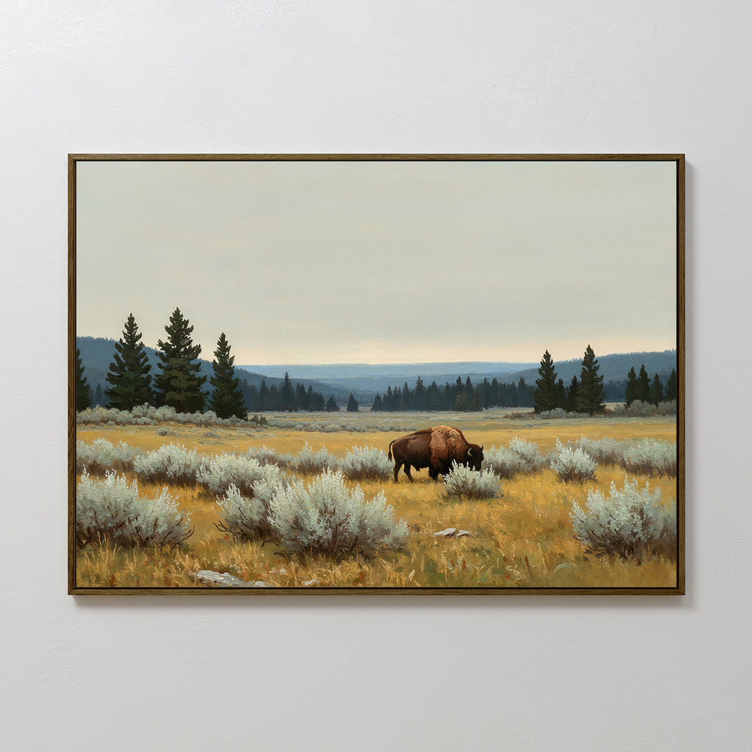 Prairie Silence Canvas Art features a bison grazing in a grassy field among shrubs and pine trees, with distant hills under a cloudy sky. This wall art adds peaceful, natural charm to any space.