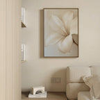 Minimalist living room in neutral tones, featuring the Pure Magnolia Canvas Art as wall decor above a beige couch, with a wooden shelf holding books and a small decorative object placed on the floor.