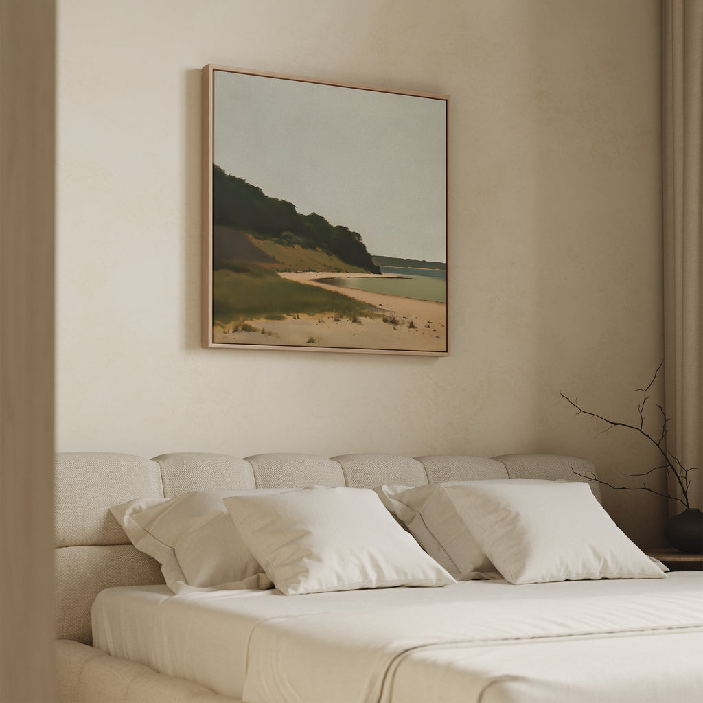 A cozy, minimal bedroom features a beige bed, white pillows, and Quiet Bend Canvas Art—a serene landscape with beach and greenery—above the headboard. Neutral walls and simple decor complete the calm, tranquil vibe.