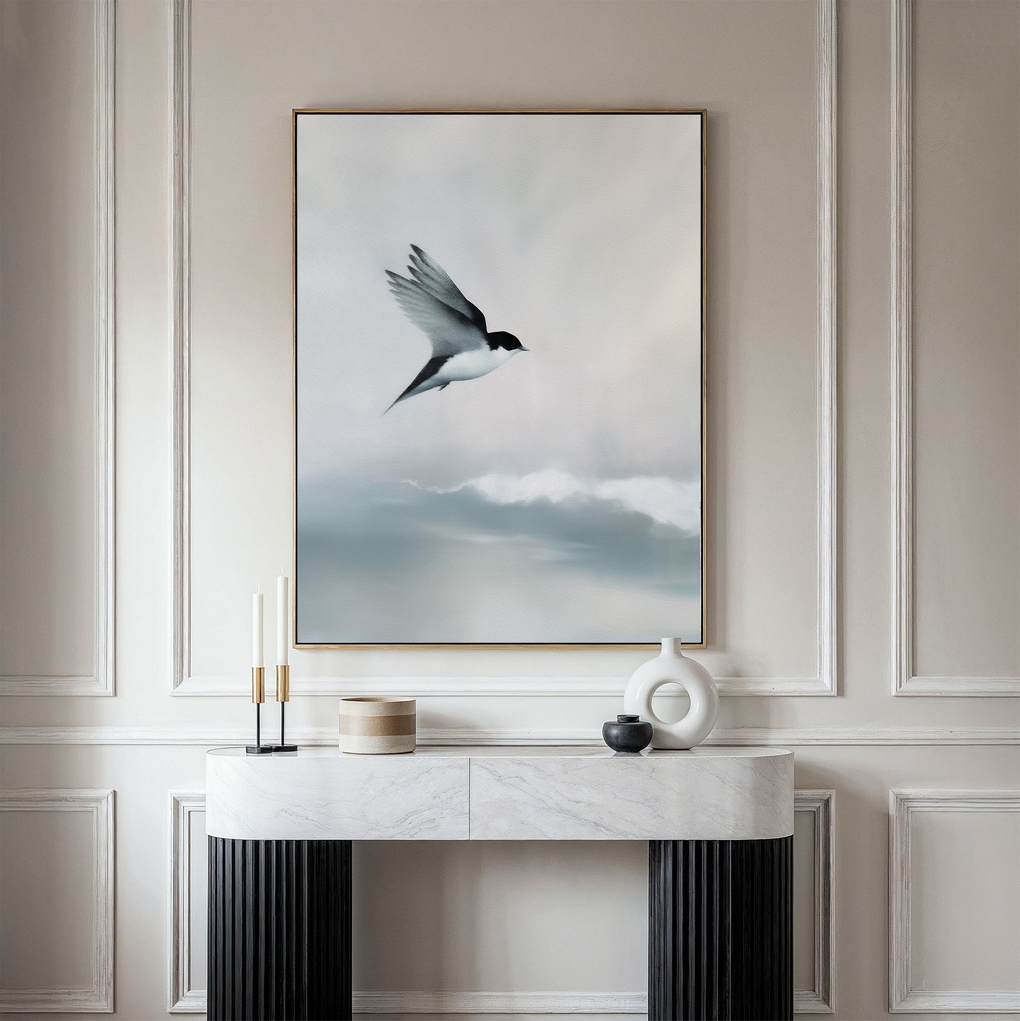 A minimalist console table sits against a beige paneled wall, topped by the Quiet Flight Canvas Art featuring a bird in flight over misty clouds, adding elegance and Nordic Park-inspired charm to the space.