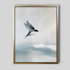 The Quiet Flight Canvas Art features a bird in flight above soft, cloudy skies, rendered in muted colors with a golden frame—ideal as minimalist wall decor or serene Nordic Park-inspired wall art.