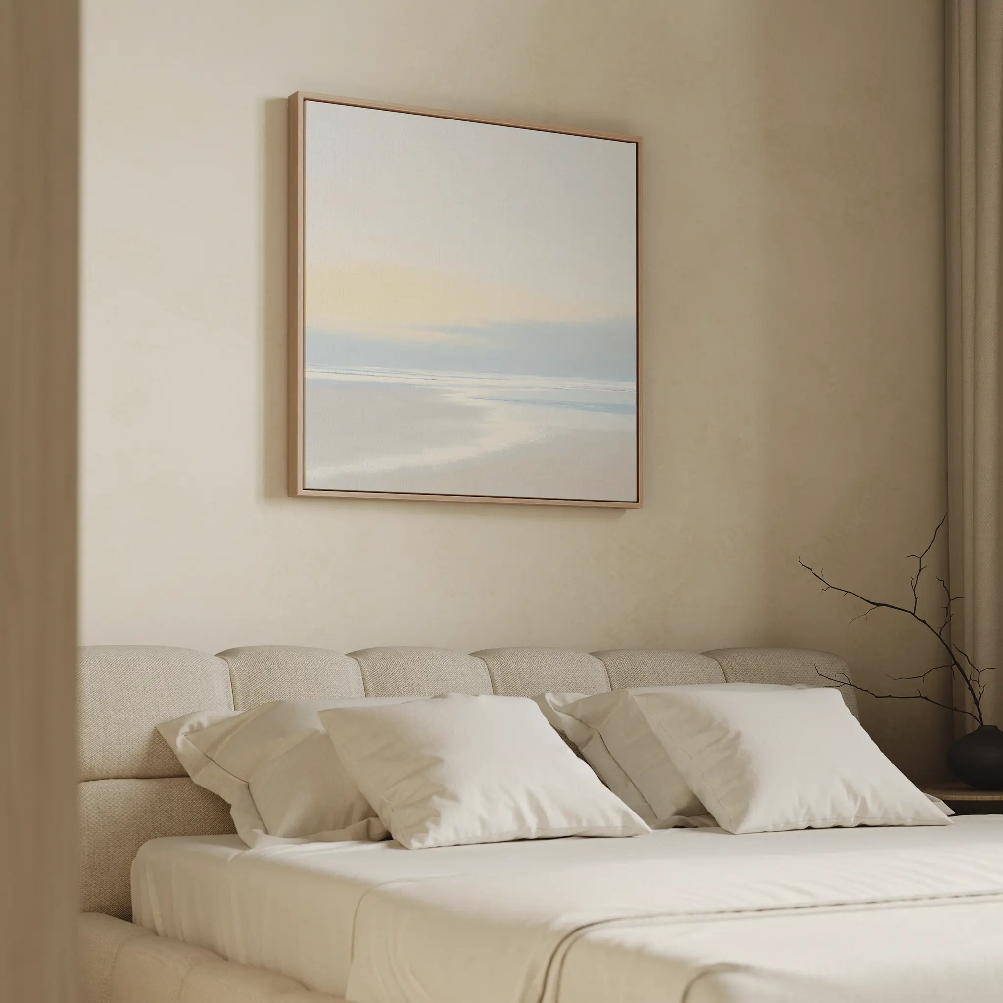 A minimal, modern bedroom features a beige upholstered bed with white bedding. Quiet Shores Canvas Art hangs above, enhancing the serene vibe, while soft natural light and beige curtains complement the tranquil coastal decor.