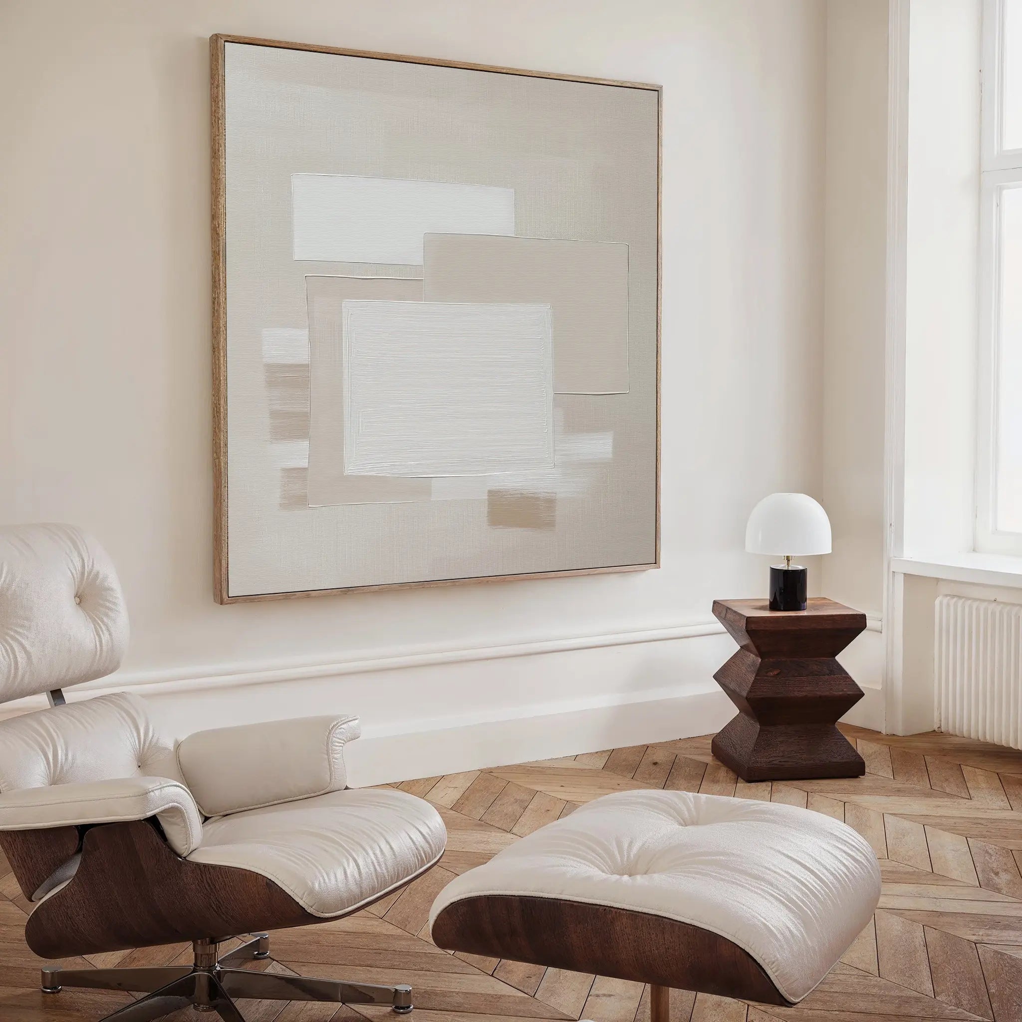 A modern, minimalist room with a cream leather lounge chair and ottoman, a dark wood side table with a white lamp, and striking neutral wall art—the Quiet Structure Canvas Art—displayed as a large abstract painting on the wall.