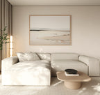 A modern living room features a light beige sectional sofa, wooden coffee table, black bowl, tall plant, and the Quiet Valley Canvas Art – Horizontal. Neutral hues and minimalist elegance create a calm, inviting atmosphere.