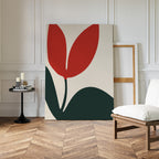 A minimalist room with wood herringbone floor, white paneled walls, a white chair, and black side table with candles features the Red Botanic Abstract Canvas Art—bold red and green leaves for striking modern living room decor.