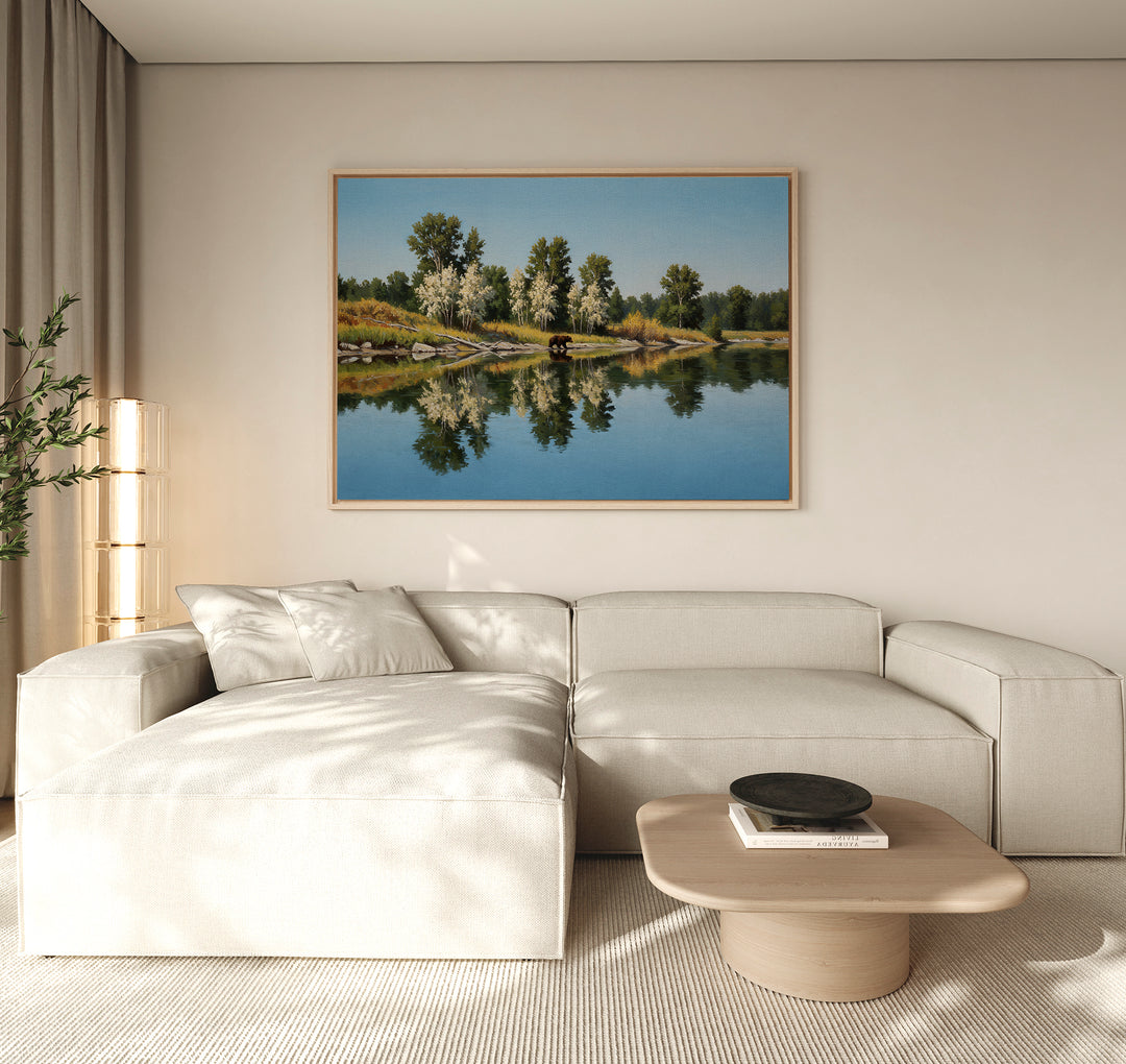 A modern living room features a light beige sectional, wooden coffee table, potted plant, and the Reflections of the Wild Canvas Art above the sofa, adding striking yet minimalist wall decor.