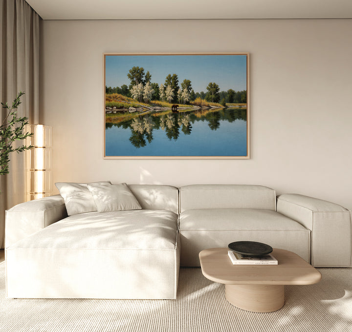 A modern living room features a light beige sectional, wooden coffee table, potted plant, and the Reflections of the Wild Canvas Art above the sofa, adding striking yet minimalist wall decor.