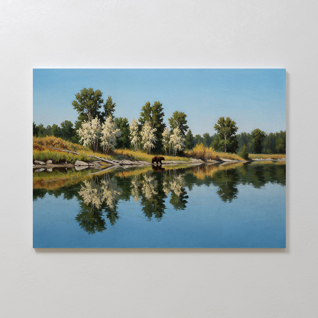 Reflections of the Wild Canvas Art features calm water mirroring trees and sky, with a brown bear near the shore amid greenery and white-blossomed trees—ideal as minimalist wall decor.
