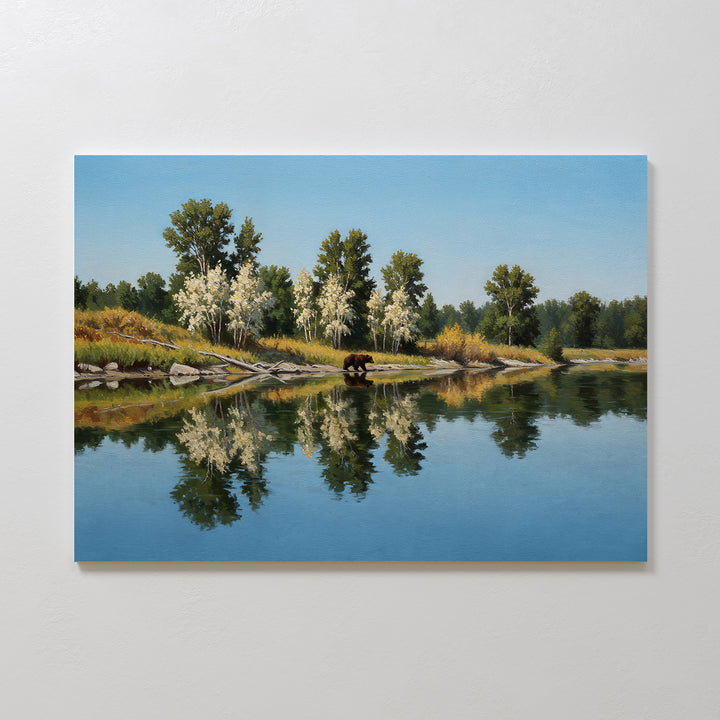 Reflections of the Wild Canvas Art features calm water mirroring trees and sky, with a brown bear near the shore amid greenery and white-blossomed trees—ideal as minimalist wall decor.