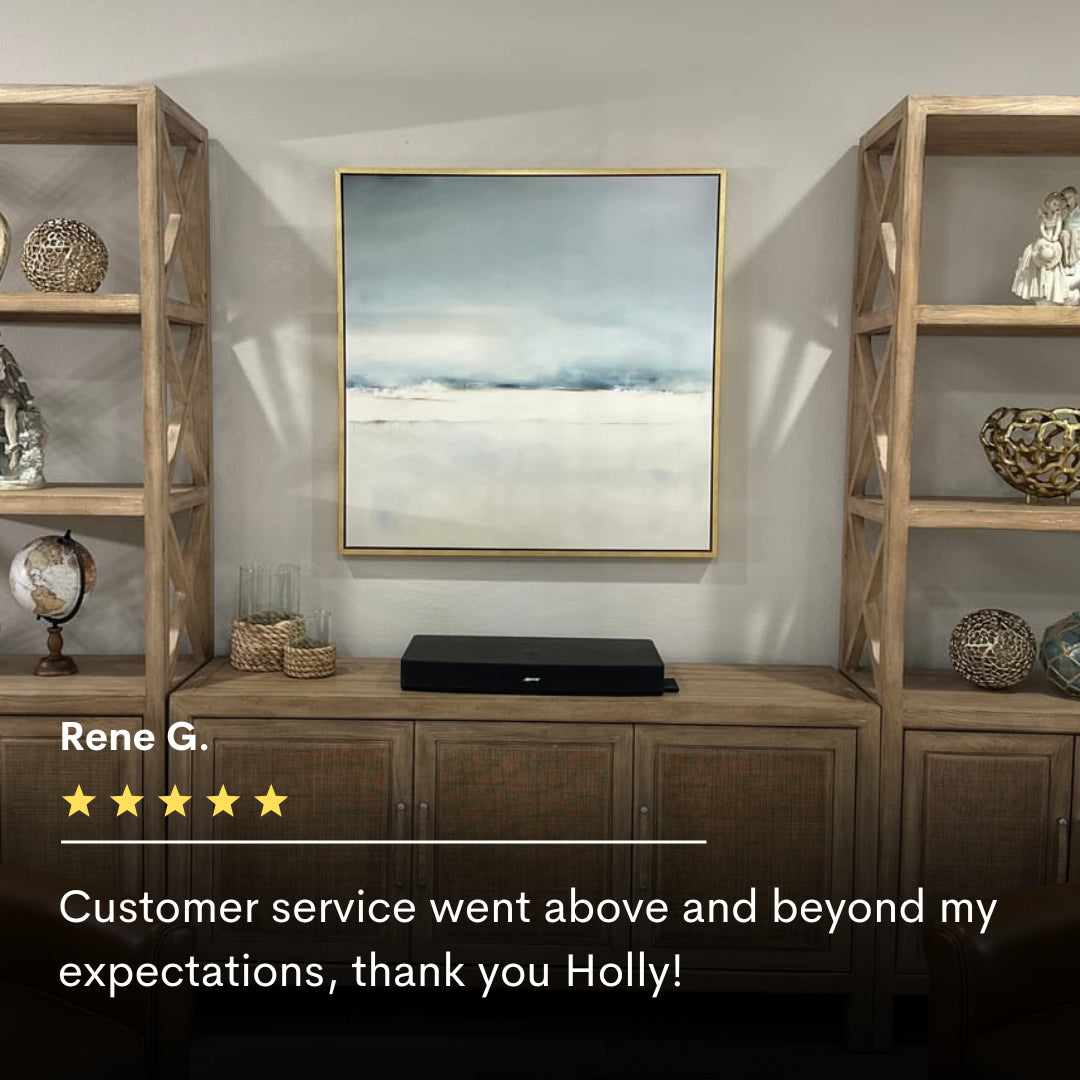 A modern living room features wooden shelves with decor, a console table, and Misty Morning Abstract Canvas Art as minimalist wall art. A five-star customer review below praises the tranquil vibe of this home decor piece.