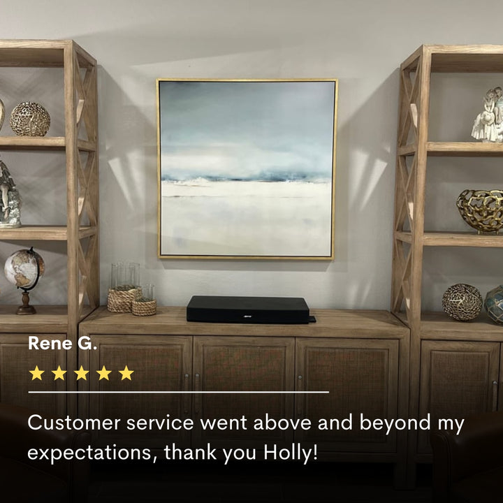 A modern living room features wooden shelves with decor, a console table, and Misty Morning Abstract Canvas Art as minimalist wall art. A five-star customer review below praises the tranquil vibe of this home decor piece.