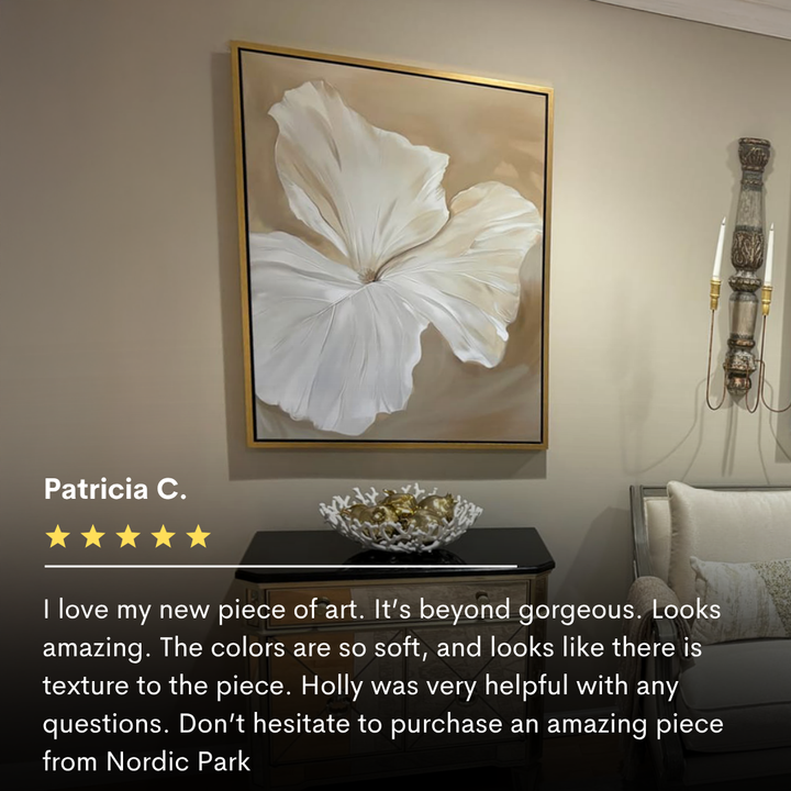 The Aqua Flora Abstract Canvas Art, showcasing a textured white flower, hangs above a black console table and decorative bowl, bringing elegance to the living room. A wall sconce and part of a white chair complete the look.