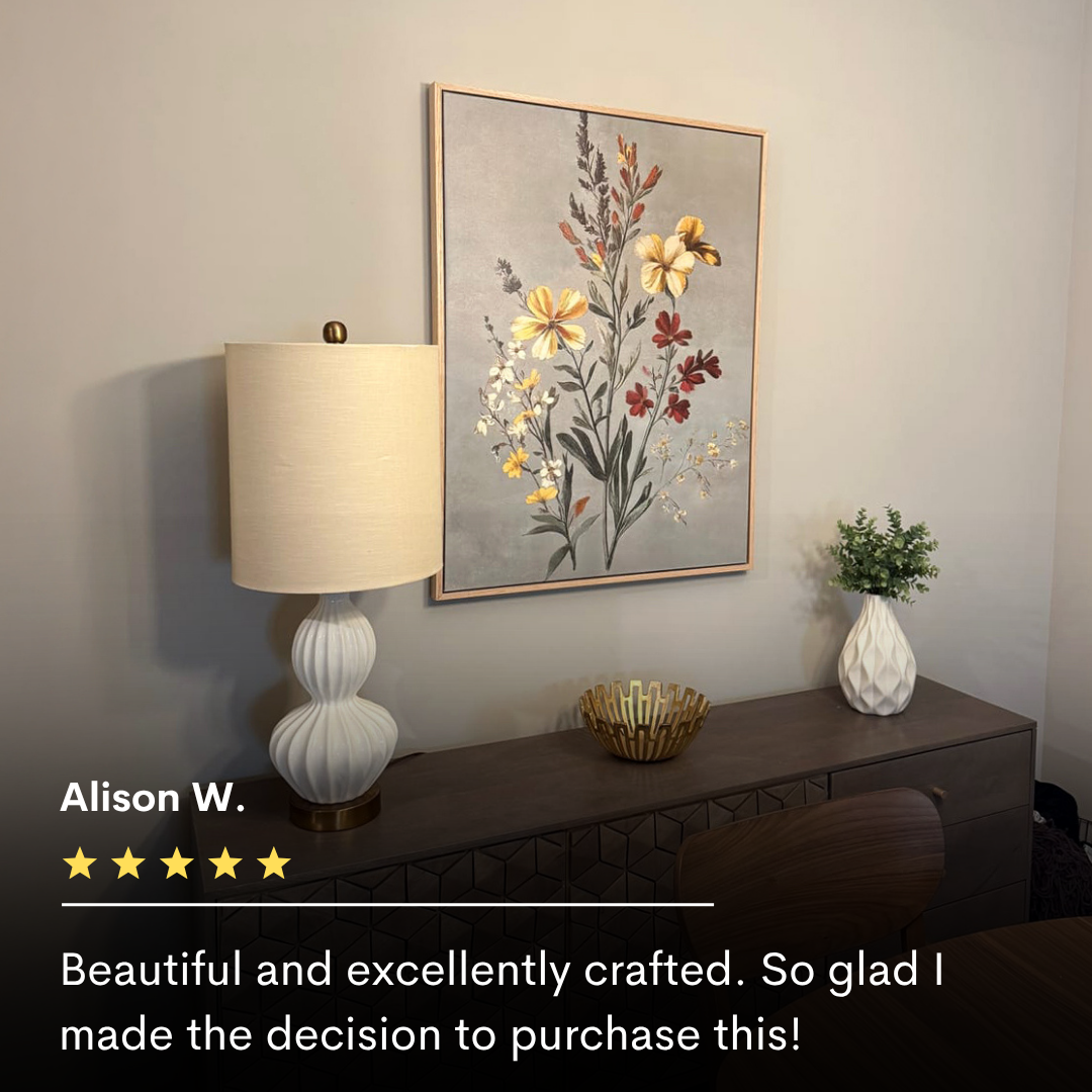 The Velvet Petals Canvas Art hangs above a modern sideboard with a white lamp, gold bowl, and greenery-filled vase. Alison W.’s five-star review praises the artwork’s beauty and quality.