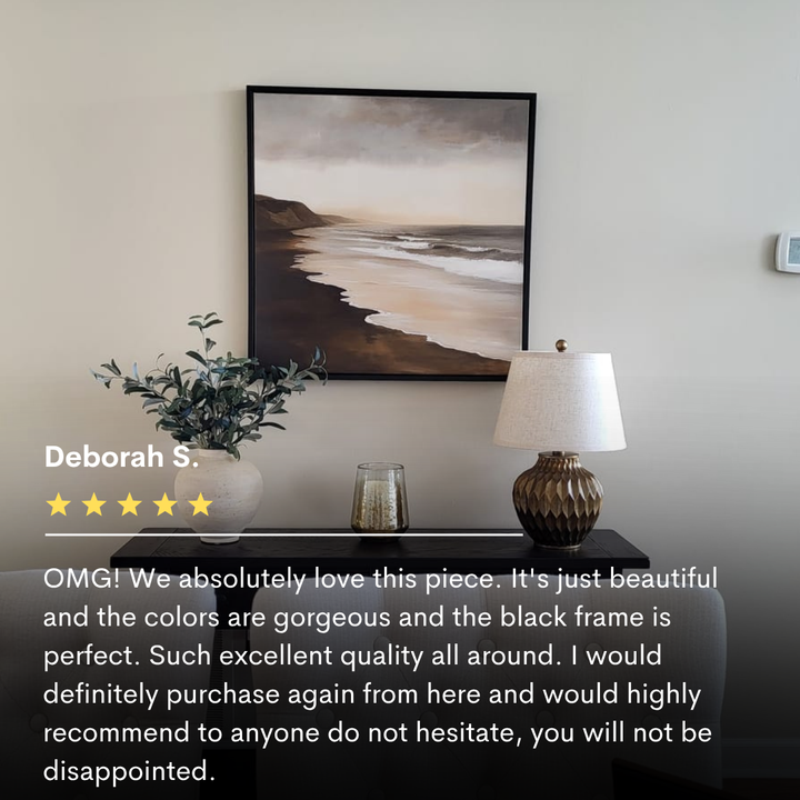 The Sandy Shoreline Canvas Art hangs above a console table with a plant, lamp, and glass candle holder. In the foreground, a five-star review highlights this coastal wall art as perfect living room decor.