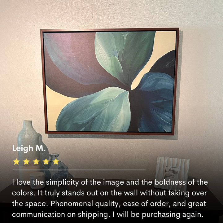 The Lush Teal Foliage Abstract Canvas Art, featuring overlapping green and blue leaves, hangs above a wooden shelf on a beige wall; perfect living room decor, it’s displayed with a vase and boasts a 5-star review.