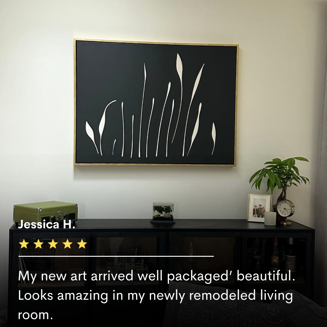 The Botanical Silhouettes Abstract Canvas Art, featuring minimalist black and white leaf shapes, hangs above a modern black console with decor in a bright living room. Overlay shows a five-star rating and glowing customer reviews.