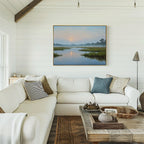 Bright living room with white shiplap walls, a large white sectional sofa, neutral and blue pillows, a rustic wooden coffee table, and the Rising Stillness Canvas Art—a landscape painting—hanging above the sofa.