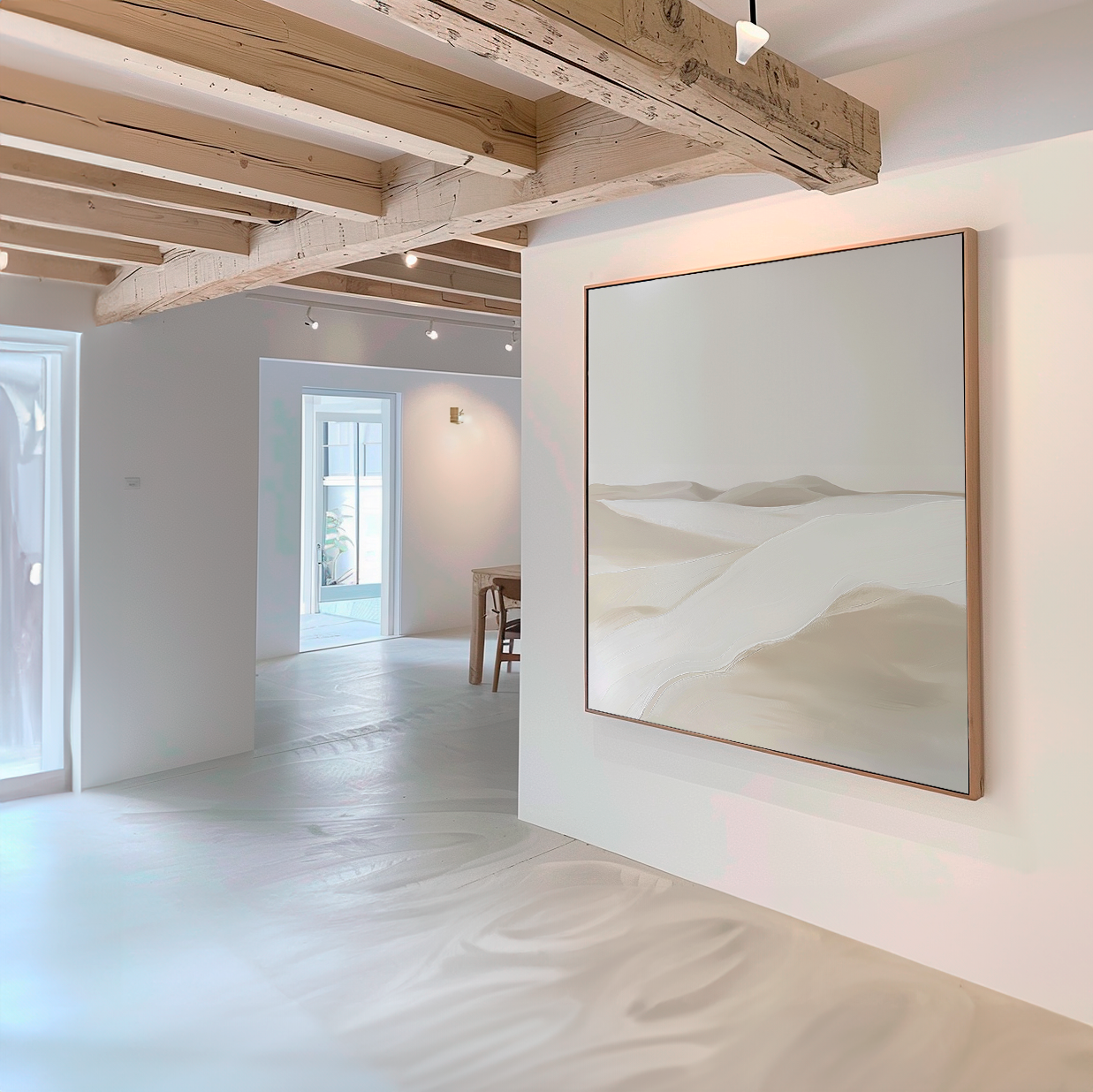 A modern, minimalist room with white walls and wooden beams showcases the Misty Vale Abstract Canvas Art—a large painting of soft beige sand dunes. Natural light fills the space, creating a calm, airy vibe ideal for living room decor.