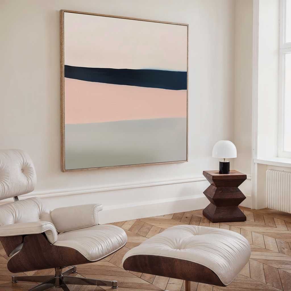 A minimal, modern living room with a white lounge chair and ottoman, the Coastal Blend Abstract Canvas Art by My Store on the wall, a small dark wood side table, a white lamp, herringbone wood flooring, and light streaming through a large window.