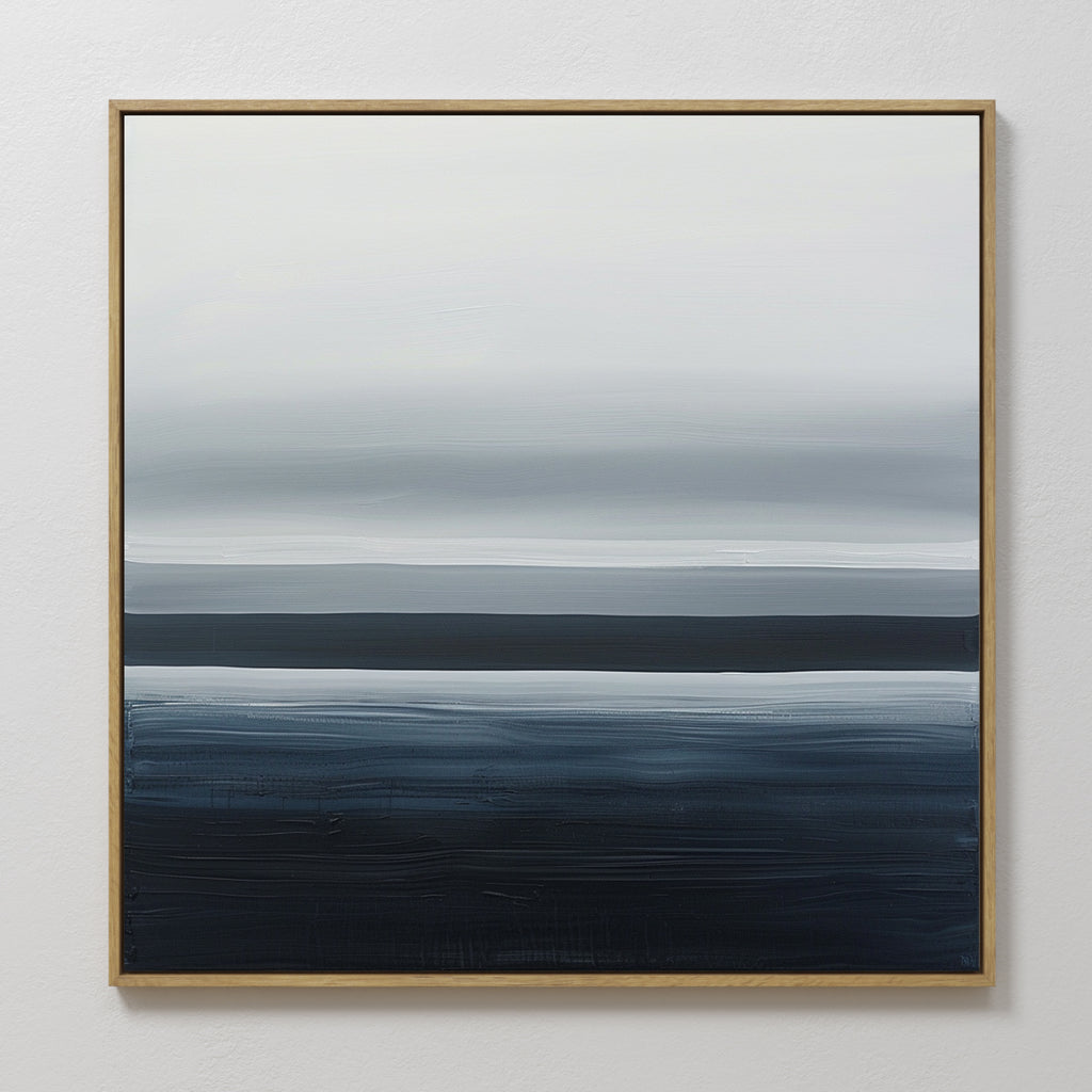 Oceanic Blur Abstract Canvas Art features horizontal layers of white, gray, and dark blue in a gold frame, blending together for a serene coastal look. Perfect minimalist wall art to enhance your living room decor with a tranquil atmosphere.