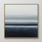 Oceanic Blur Abstract Canvas Art features horizontal layers of white, gray, and dark blue in a gold frame, blending together for a serene coastal look. Perfect minimalist wall art to enhance your living room decor with a tranquil atmosphere.