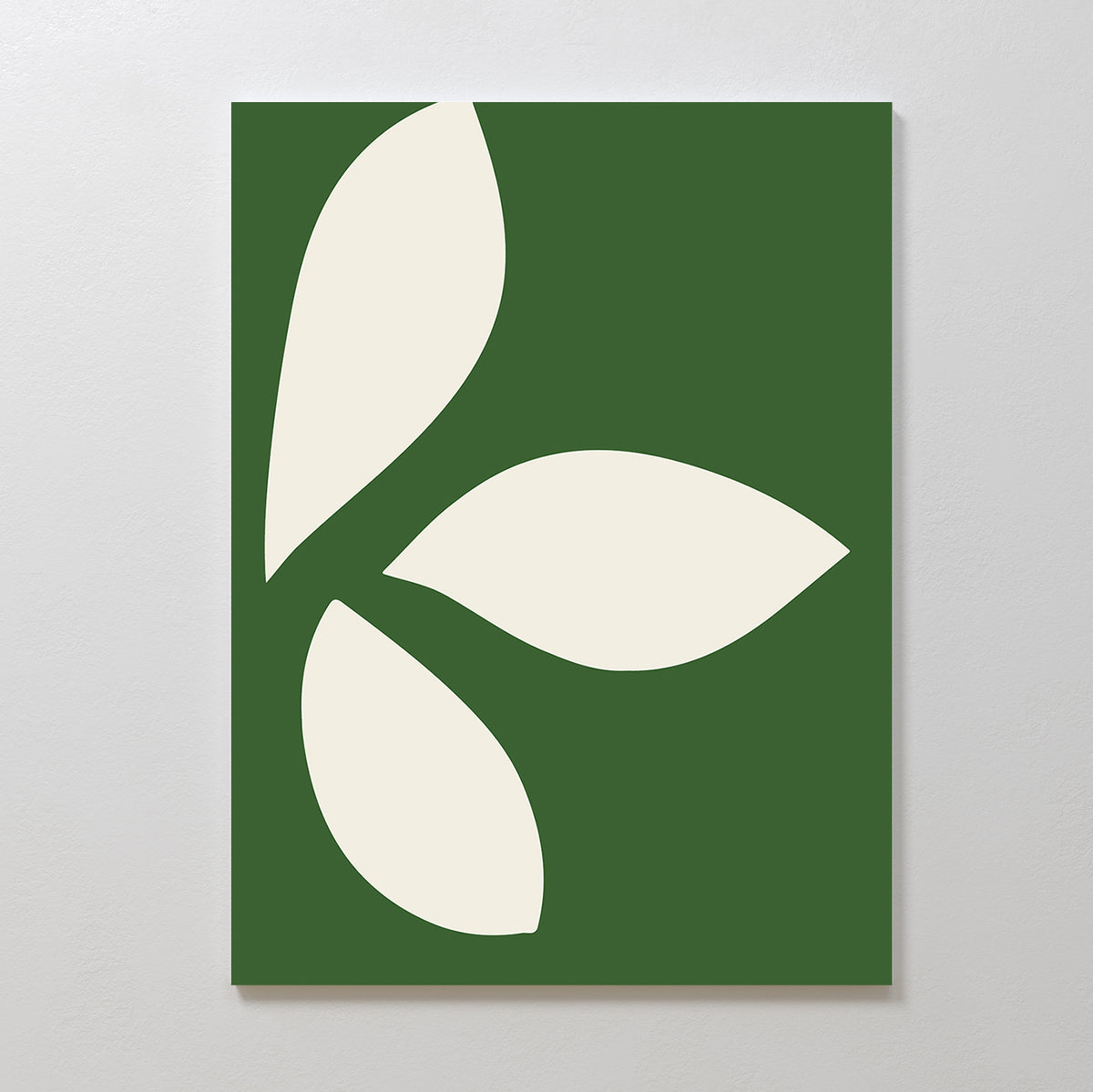 The Leaf Silhouette Abstract Canvas Art displays three large off-white leaf-like shapes on a green rectangular background, creating modern, minimalist wall decor for any plain light wall.